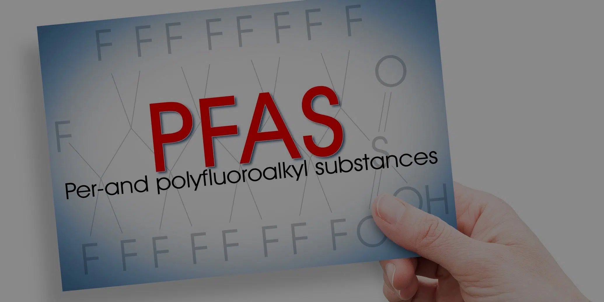 Hand holding a card with 'PFAS,' chemicals linked to water contamination in Colorado.